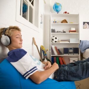 a young boy listening to headphones on a beanbag chair in his room